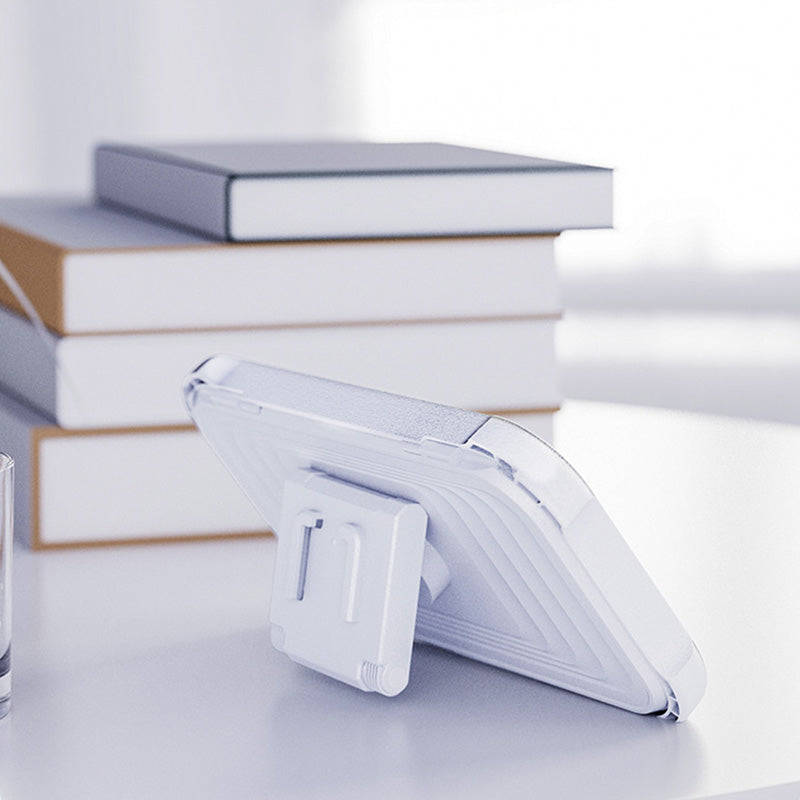 Retractable phone holder folded into a desktop stand beside books